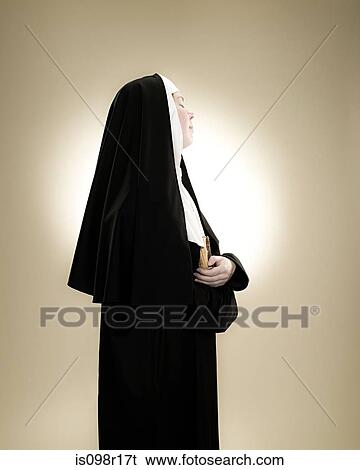 Profile of a nun holding a bible View Large Photo Image Stock Photograph - Profile of a nun holding a bible. Fotosearch