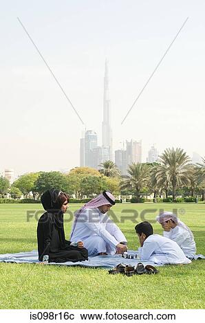 Stock Image - A family sat in a park playing chess. Fotosearch
