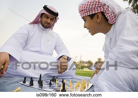 Stock Image - A father and son playing chess in a park. Fotosearch