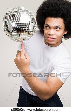 Stock Photograph - A young man balancing a disco ball. Fotosearch