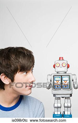 Teenage boy looking at a robot View Large Photo Image Stock Image - Teenage boy looking at a robot. Fotosearch
