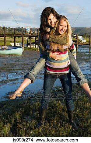 Girl giving piggyback to friend View Large Photo Image Picture - Girl giving piggyback to friend. Fotosearch