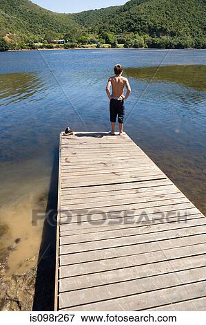 Teenage boy on a jetty View Large Photo Image Stock Photo - Teenage boy on a jetty. Fotosearch