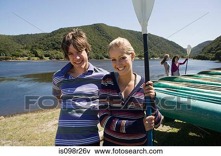 Stock Photo - Teenager couple by canoes. Fotosearch