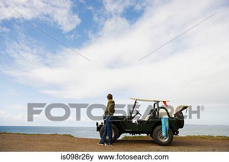 Young man by sea with off road vehicle View Large Photo Image Stock Photo - Young man by sea with off road vehicle. Fotosearch