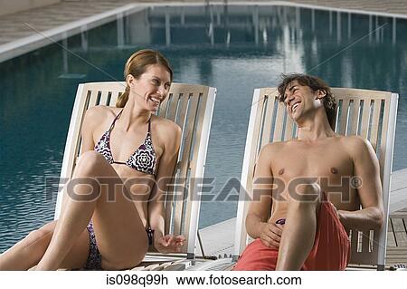 Couple relaxing by swimming pool View Large Photo Image Stock Image - Couple relaxing by swimming pool. Fotosearch