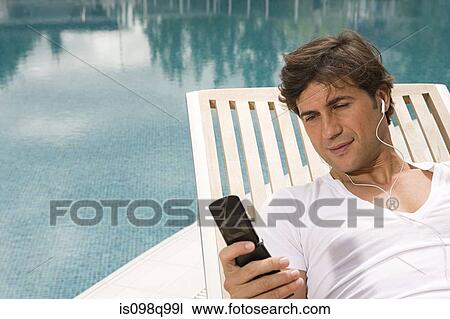 Man listening to music on cellular phone View Large Photo Image Stock Image - Man listening to music on cellular phone. Fotosearch