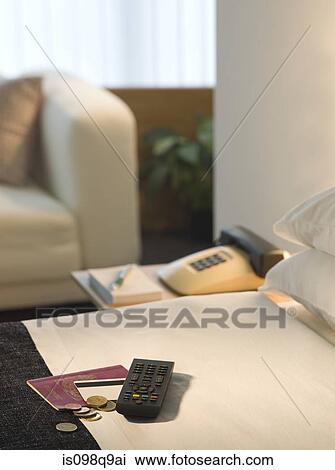 Stock Image - Passport and remote control on a hotel bed. Fotosearch