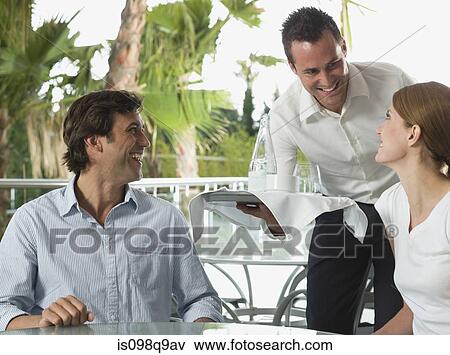 Stock Photo - Waiter serving a couple. Fotosearch