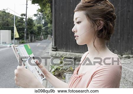 Stock Image - Young woman looking at map. Fotosearch