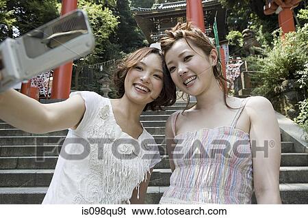 Young women at shrine with camera telephone View Large Photo Image Stock Photograph - Young women at shrine with camera telephone. Fotosearch