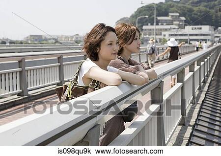 Stock Image - Young women on bridge. Fotosearch