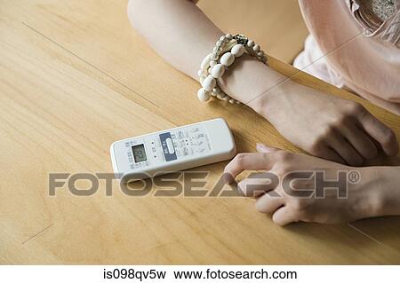 Stock Photo - Woman with air conditioning remote control. Fotosearch
