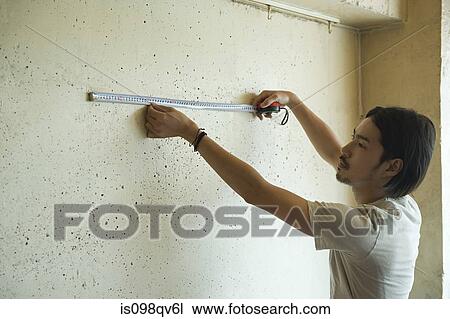Young man measuring wall View Large Photo Image Stock Image - Young man measuring wall. Fotosearch