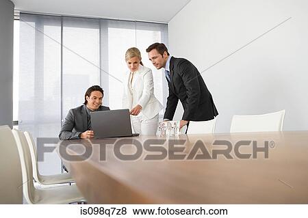 Stock Photo - Colleagues looking at laptop. Fotosearch