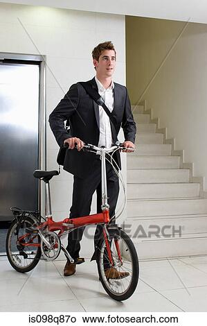 Picture - Man in office with bike. Fotosearch