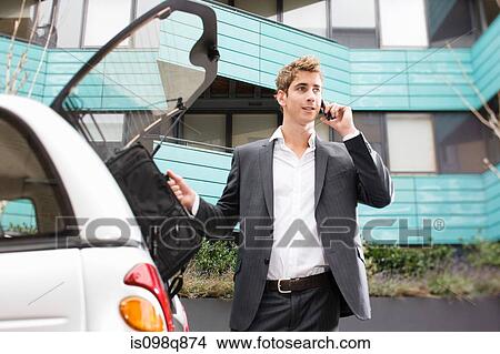 Man on cellphone by car View Large Photo Image Picture - Man on cellphone by car. Fotosearch