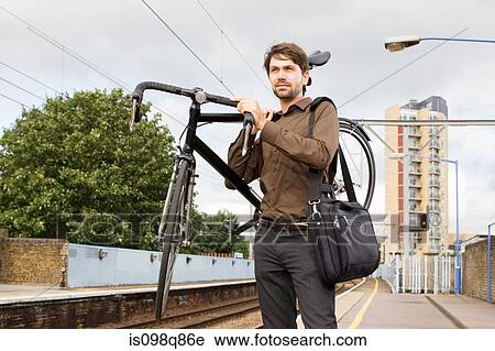 Stock Image - Man with bike at train station. Fotosearch