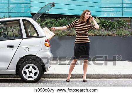 Woman on cellphone by car View Large Photo Image Stock Photo - Woman on cellphone by car. Fotosearch