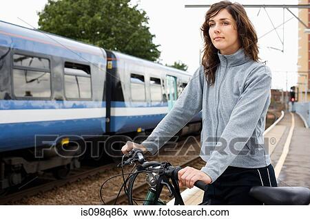 Woman with bike at train station View Large Photo Image Stock Photo - Woman with bike at train station. Fotosearch