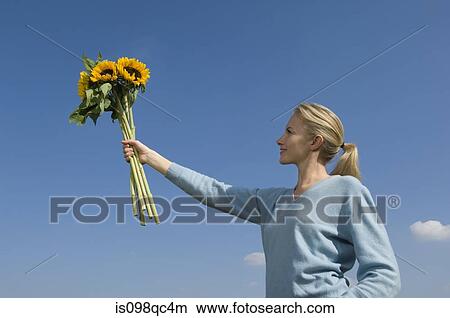 Picture - Woman holding bunch of sunflowers. Fotosearch