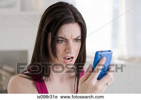 Stock Image - Angry woman looking at cellphone. Fotosearch
