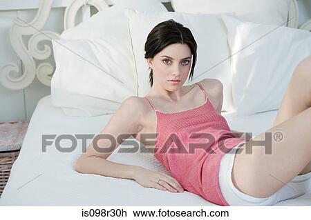 Young woman lying on bed View Large Photo Image Stock Image - Young woman lying on bed. Fotosearch