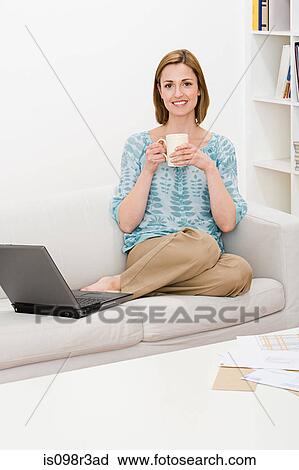 Stock Image - Woman sitting on sofa. Fotosearch