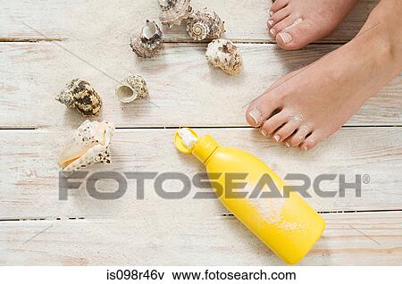 Stock Photo - Female feet with shells and suncream. Fotosearch