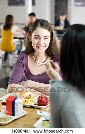 Stock Image - Female school students having lunch. Fotosearch