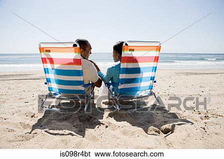 Couple relaxing on a beach View Large Photo Image Stock Photograph - Couple relaxing on a beach. Fotosearch