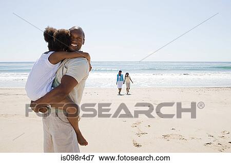 Stock Photo - Father carrying daughter on beach. Fotosearch