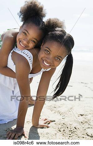 Stock Photograph - Sisters playing on a beach. Fotosearch