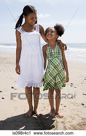 Sisters standing on a beach View Large Photo Image Stock Image - Sisters standing on a beach. Fotosearch