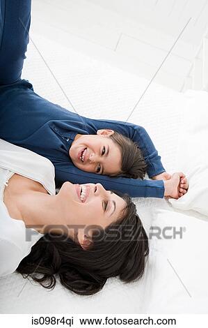 Mother and daughter lying on bed View Large Photo Image Stock Image - Mother and daughter lying on bed. Fotosearch