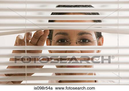 Stock Image - Businesswoman behind blinds. Fotosearch