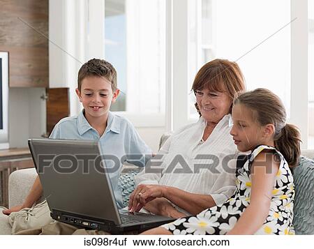 Stock Image - Woman and grandchildren with laptop. Fotosearch
