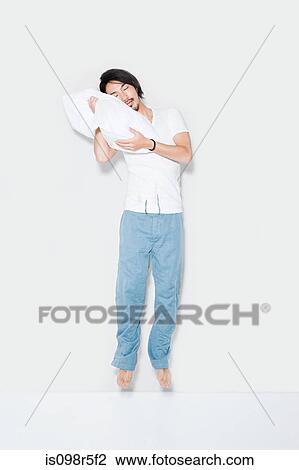 Stock Image - Jumping man with pillow. Fotosearch