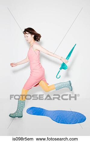 Woman jumping over puddle View Large Photo Image Picture - Woman jumping over puddle. Fotosearch
