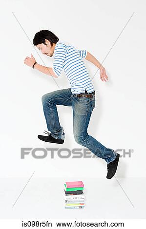 Young man jumping over books View Large Photo Image Picture - Young man jumping over books. Fotosearch