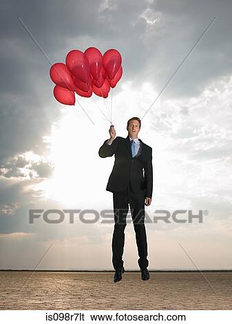 Businessman holding a bunch of red balloons View Large Photo Image Stock Photograph - Businessman holding a bunch of red balloons. Fotosearch