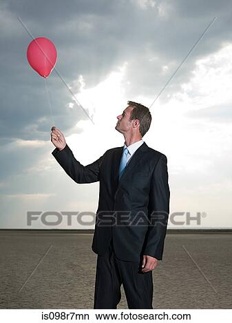 Businessman holding a red balloon View Large Photo Image Picture - Businessman holding a red balloon. Fotosearch