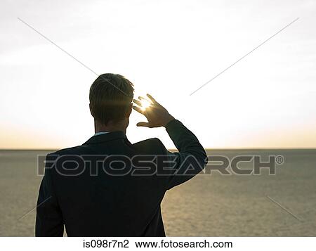 Stock Image - Businessman looking into the sun. Fotosearch