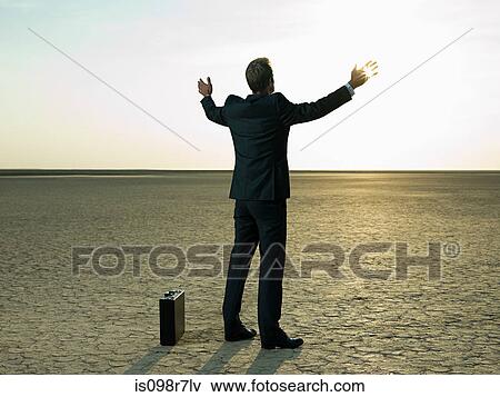 Businessman raising his arms in a desert View Large Photo Image Stock Photo - Businessman raising his arms in a desert. Fotosearch