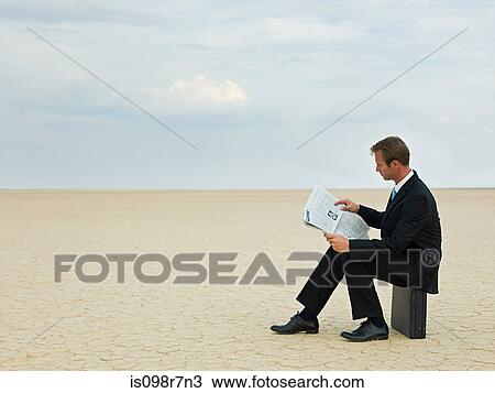 Businessman reading a newspaper in the desert View Large Photo Image Stock Image - Businessman reading a newspaper in the desert. Fotosearch