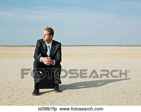 Businessman sitting on a briefcase in the desert View Large Photo Image Stock Photography - Businessman sitting on a briefcase in the desert. Fotosearch