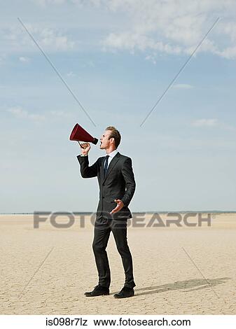 Businessman using a megaphone in the desert View Large Photo Image Stock Photo - Businessman using a megaphone in the desert. Fotosearch