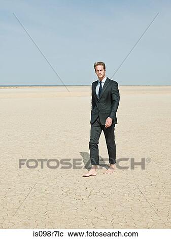 Businessman walking barefoot in the desert View Large Photo Image Stock Image - Businessman walking barefoot in the desert. Fotosearch