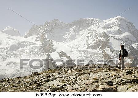 Picture - Hiker near an ice covered mountain. Fotosearch