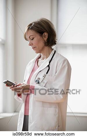 Doctor looking at cellphone View Large Photo Image Stock Image - Doctor looking at cellphone. Fotosearch